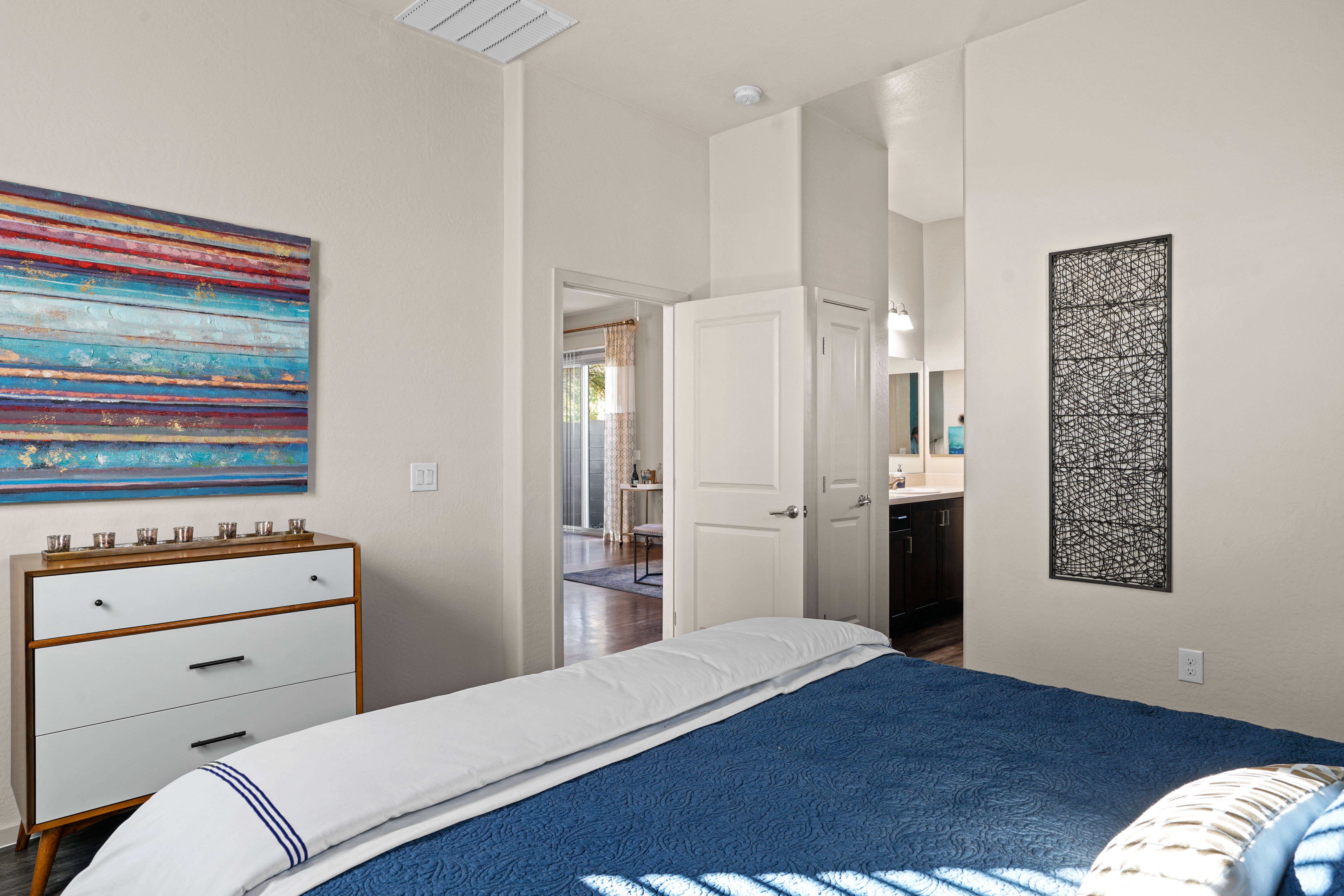 a bedroom with a bed and a bathroom with a sink at Olive Queen Creek Apartments, Queen Creek, AZ